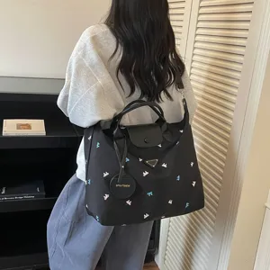 Gedetailleerd overzicht van de lichte nylon reistas met strik borduursel en lederen flap.