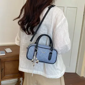Detail der blauen Stepp-Handtasche aus Denim mit schwarzem Griff und silbernem Anhänger.