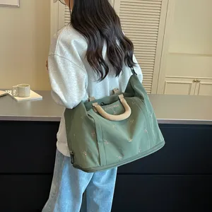 Bolso de viaje de lona verde de gran capacidad con bordado de lazos para viajes cortos.