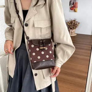 Close-up detail view of the brown polka dot crossbody phone bag with toggle button.