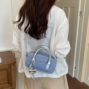 Detailansicht der lässigen Denim gesteppten Kissentasche mit silbernen Griffen und Anhänger.