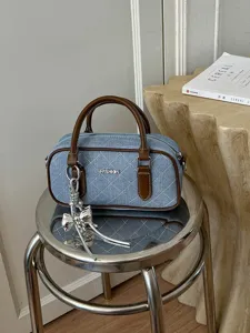 Gesteppte Jeans-Bowlinghandtasche mit braunen Ledergriffen und Schleifenanhänger für Damen.