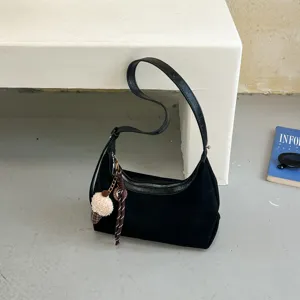 Detailfoto van zwarte schoudertas in hobo-stijl, casual dumplingsvorm met zachte suède textuur.
