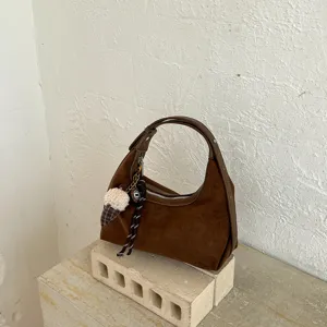 Detail van bruine suède hobo tas, zachte textuur en chique eikel hanger voor stijl.