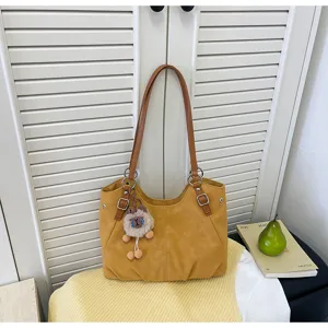 Vista dettagliata della borsa tote vintage gialla con manici marroni e un simpatico ciondolo di peluche.