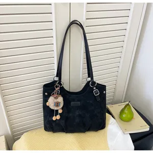 Dettaglio borsa tote vintage nera con ciondolo di peluche e doppie cinghie per ufficio.
