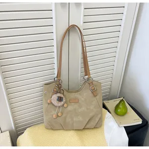 Vista ravvicinata dettagliata di borsa a tracolla tote beige vintage con grazioso ciondolo in peluche
