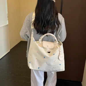 Details van grote canvas shopper tas met borduursel en stijlvol driehoek logo.