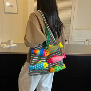 Vista dettagliata di una borsa shopper in maglia a righe colorata con simpatici peluche.