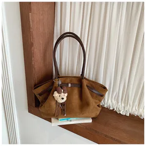 Brown suede pleated tote bag with dark handles and cute bear charm for daily commuting style.