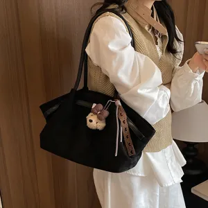 Close-up detail shot of the black canvas tote bag with bear charm and chic strap design accent.