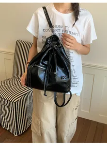 Detailansicht des schwarzen PU-Leder-Kordelzug-Rucksacks mit weicher Textur und Metallschnallen.