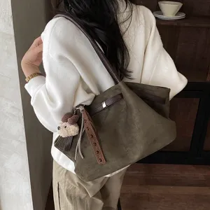 Detailed view of women suede shoulder tote bag with vintage design and charm pendant.