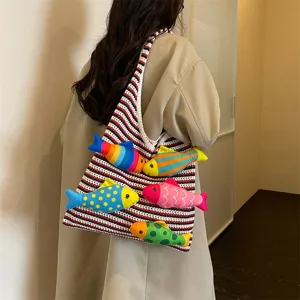 Dettaglio di una borsa in maglia con decorazioni di pesci di peluche colorati e a righe.