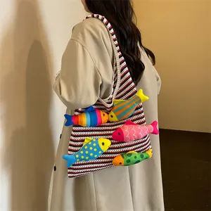 Vista ravvicinata dell'elegante borsa shopper in maglia a righe decorata con pesci di peluche.