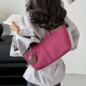 Detail shot of retro suede underarm shoulder bag in magenta with brown leather trim details.
