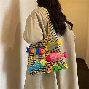 Vista dettagliata di una borsa shopper in maglia con simpatici pesci di peluche colorati.
