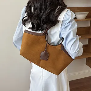 Detail shot of the elegant brown suede shoulder bag showcasing its vintage casual underarm style.