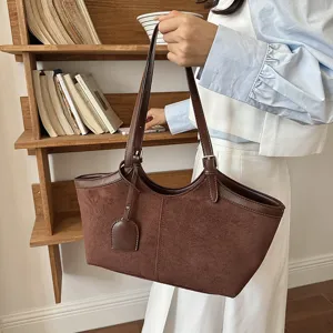 Detailed view of a vintage brown suede tote bag, stylish shoulder bag with contrast trim.