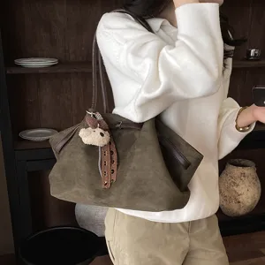 Detailed view of the dark green pleated tote bag with cute bear pendant and brown strap.