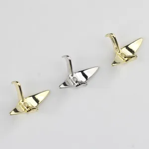 Close-up of alloy origami crane charms, metal spacer beads for DIY jewelry making.