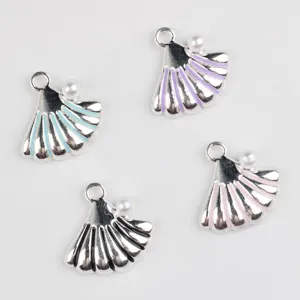 Gros plan de pendentifs coquillage en alliage coloré avec perle pour bijoux faits maison.