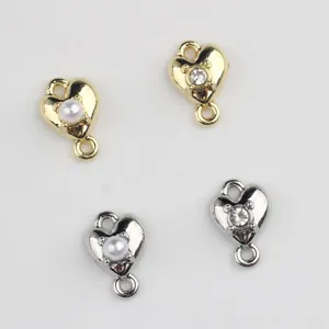 Detailed shot of heart-shaped alloy connectors with pearl and zircon for DIY jewelry making.