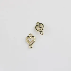 Detail view of gold alloy heart double-loop connector with pearl and zircon for DIY jewelry.