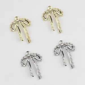 Detail shot of alloy hollow lace bow pendants in gold and silver, perfect for DIY jewelry making.