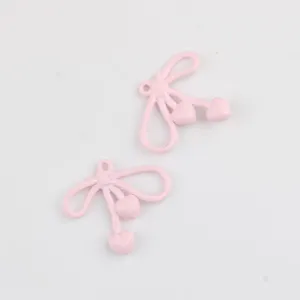 Detailed close-up shot of cute pink enamel bow alloy charms for DIY jewelry making.