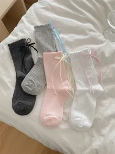 Detail view of sweet Japanese JK style mid-tube socks with ribbon bowknots and lace cuffs.
