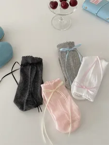 Close-up detail of cute Japanese JK style ruffle mid-calf socks with sweet ribbon bows.