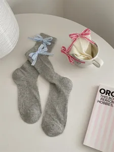 Closeup of Japanese style grey and white ribbed socks featuring cute plaid bow accents.