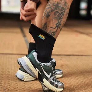 Gros plan de chaussettes de skate en coton noir avec broderie colorée, détail streetwear.