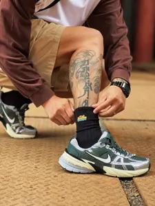 Gros plan détaillé de chaussettes mi-mollet noires tendance cityboy avec broderies colorées.