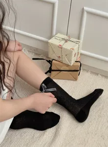 Detail shot of Japanese style black mid-tube socks with a chic plaid bow for women.