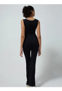 Back view detail of black ribbed seamless yoga jumpsuit, elastic activewear fabric texture.