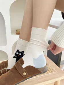 Primo piano dettagliato di calzini in cotone con gatto ricamato abbinati a zoccoli casual.
