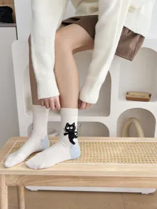 Vista dettagliata di calzini bianchi da donna a metà altezza con gatto nero ricamato in cotone.