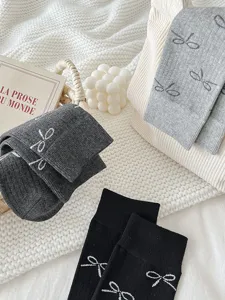 Detailed view of grey cotton mid-calf socks featuring elegant bow patterns and cozy knit scene.