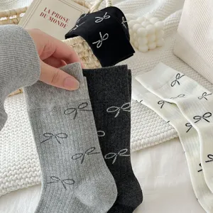 Close-up detail of women's bow print mid-calf socks in assorted neutral colors and white.