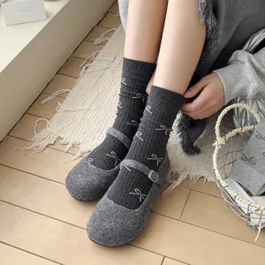 Detailed close-up view of grey cotton mid-tube socks featuring cute white bow patterns.