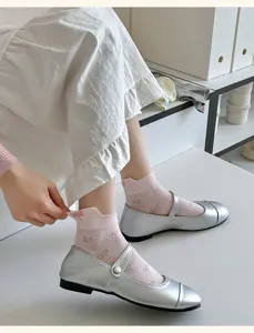 Close-up detail of women's short socks with cute back bow embroidery and silver flat shoes.