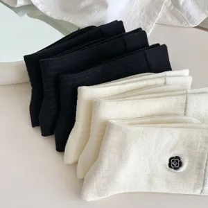 Vista dettagliata di calzini medi da donna in cotone nero e bianco con delicato ricamo floreale.