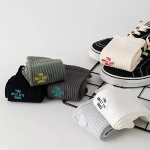 Detailansicht trendiger Rippstrumpf-Socken mit besticktem Slogan in verschiedenen Farben.