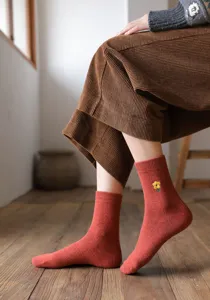 Gros plan de chaussettes en laine pour femmes avec broderie florale 3D couleur rouge.