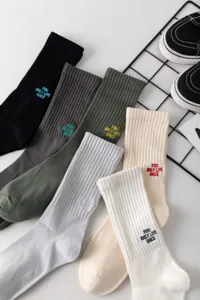 Detailansicht bunter Herren-Mittelsocken mit besticktem Slogan-Text und Rippenbündchen.