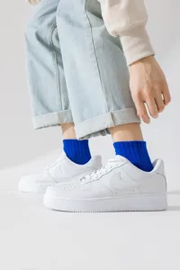 Detail shot of vibrant royal blue ribbed crew socks paired with classic white low-top sneakers.