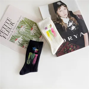 Chaussettes mi-hautes en coton avec lettres brodées et motif éclaboussures, noir et blanc.
