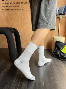 Detail shot of men's white mid-calf athletic socks with blue embroidery and rib design.
